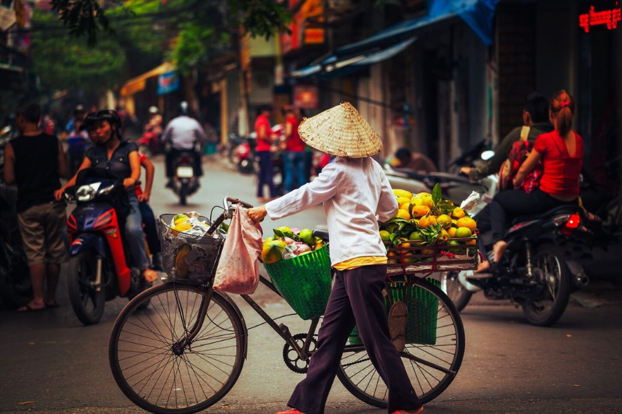 Vietnamese street vendor selling fruits by bicycle in Hanoi, featured in Indochina tours
